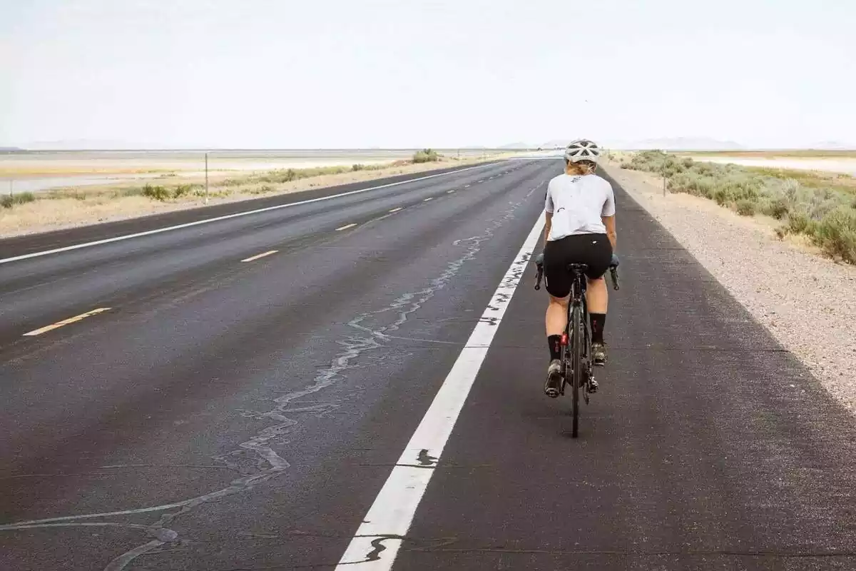 Una persona yendo en bicicleta por una carretera desierta