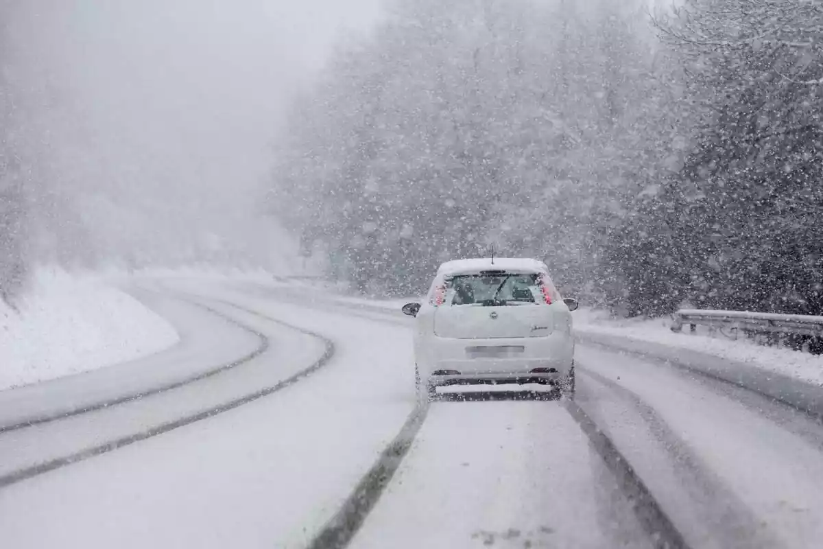 Un coche atravesando una fuerte nevada en una carreta en Galicia con todo cubierto con varios centímetros