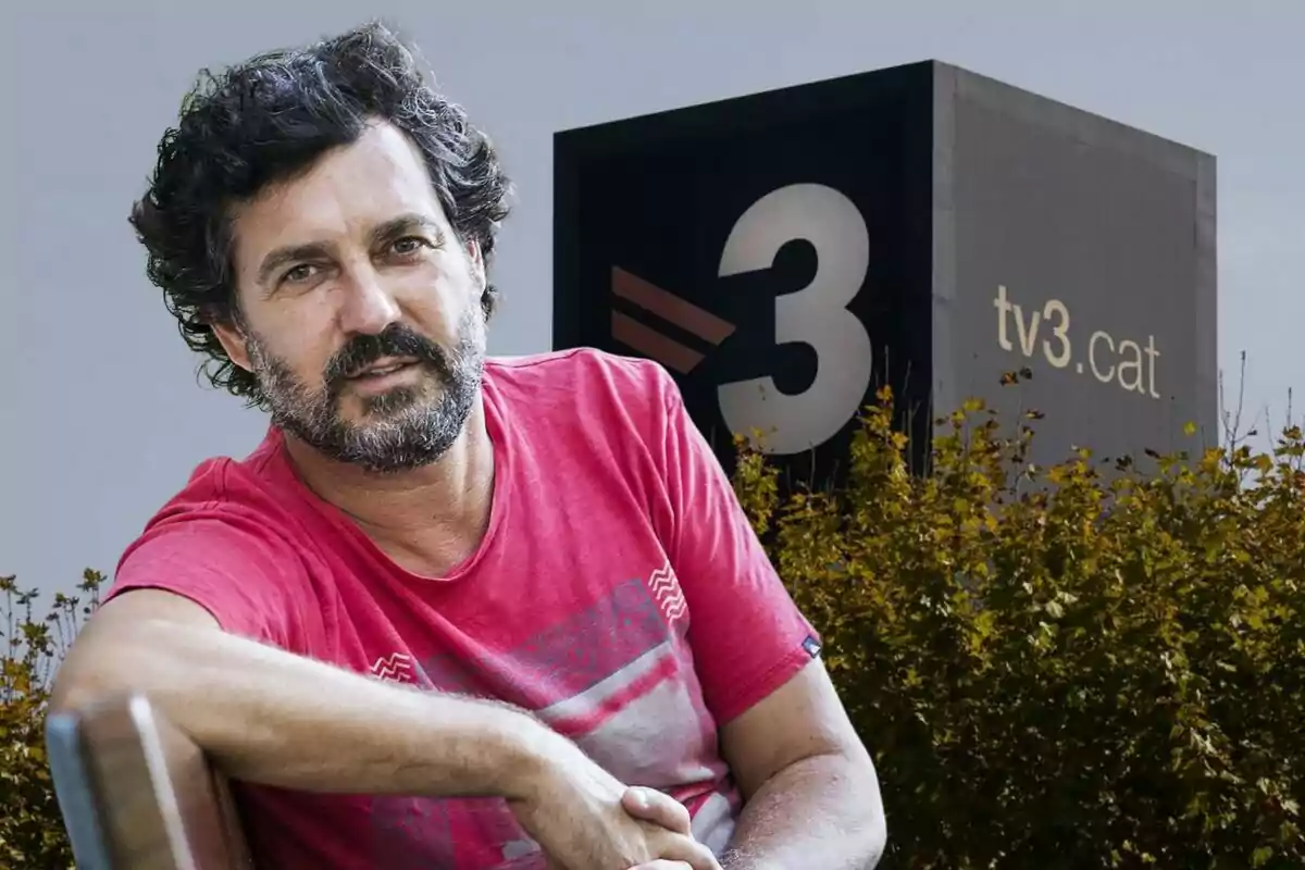 Un hombre con barba y cabello rizado, vestido con una camiseta roja, está sentado frente a un edificio con el logotipo de "tv3.cat".