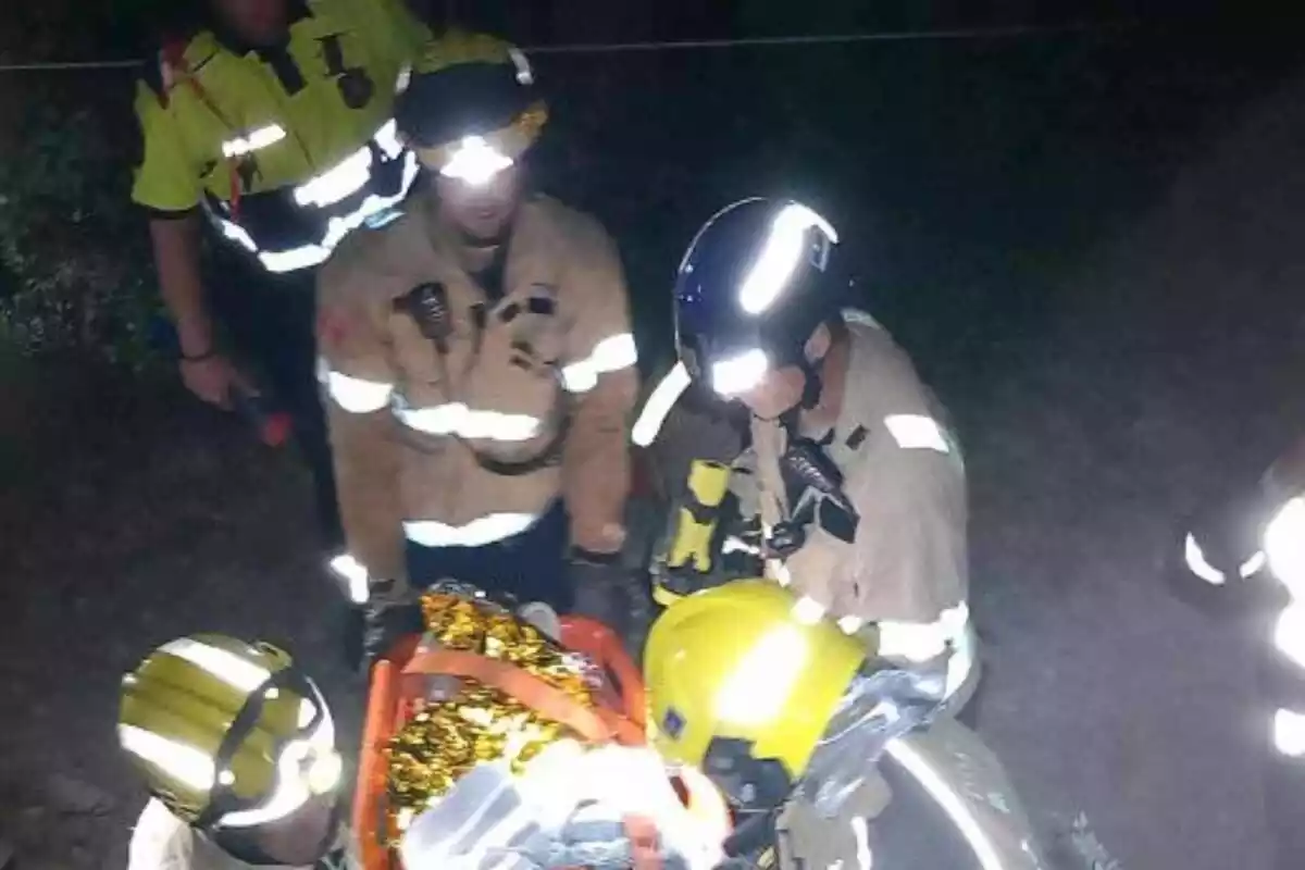 Imagen de los Bombers de la Generalitat con una camilla acudiendo al rescate de un joven que había caído con su coche por un precipicio en el Pallars Jussà, en Sort